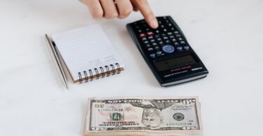 crop unrecognizable accountant using calculator near pile of american dollars