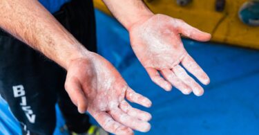 man showing hands with talc during climbing training