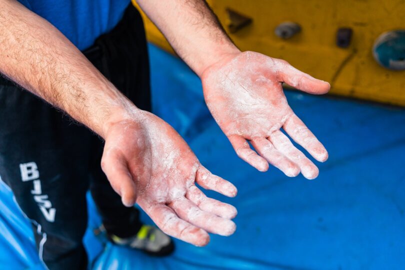 man showing hands with talc during climbing training